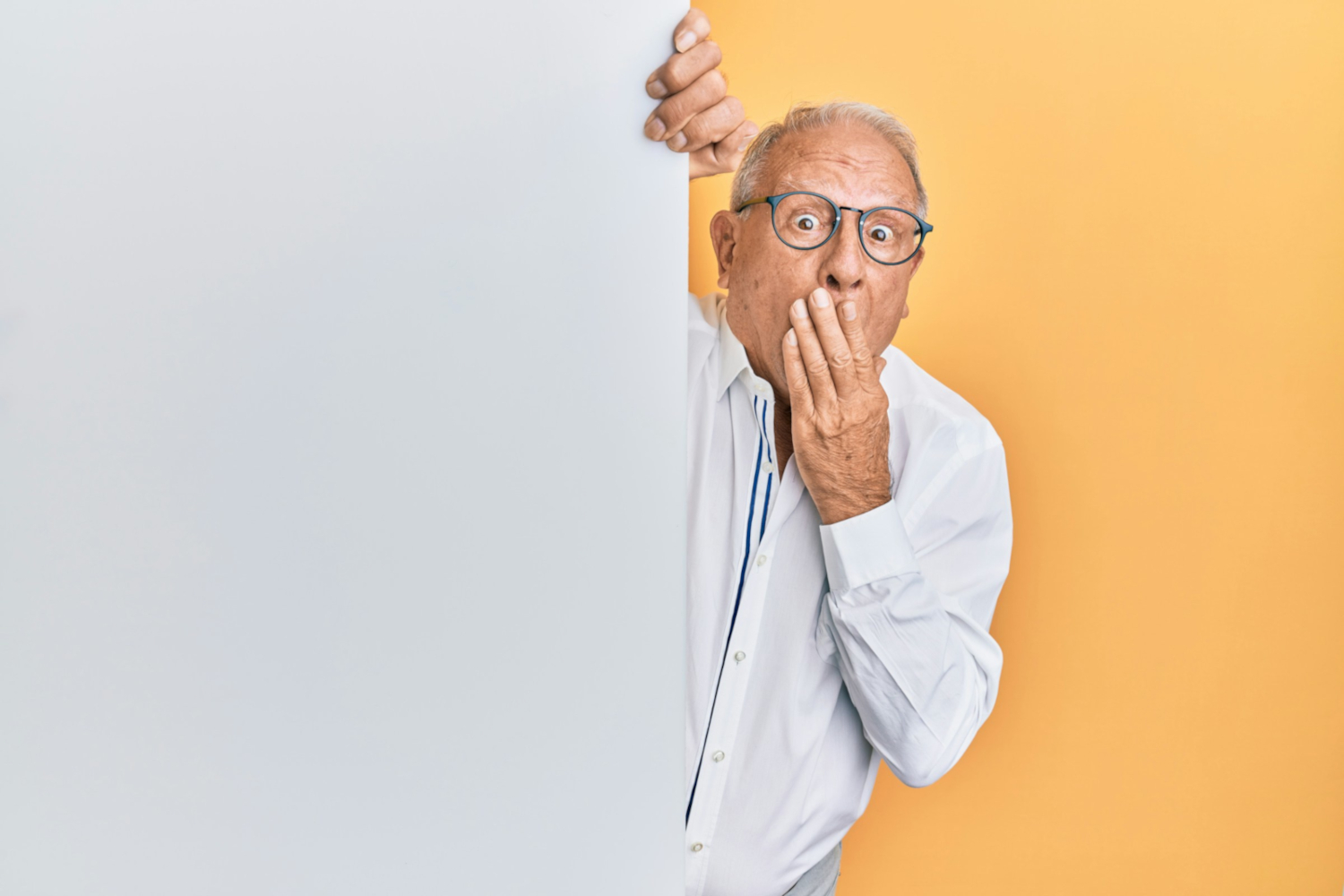 older man peering around corner looking amazed