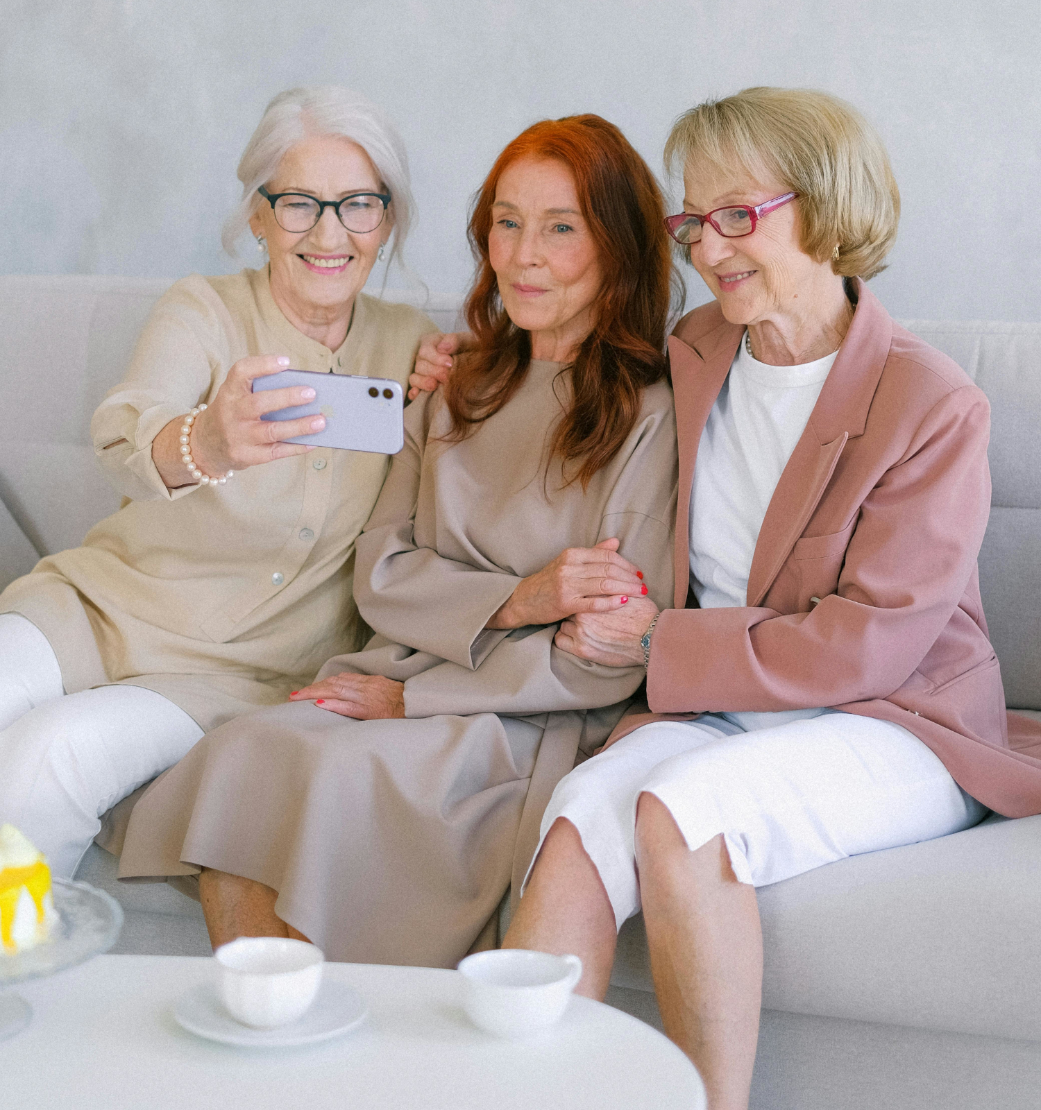 senior women sitting on couch smiling taking a selfie picture with phone
